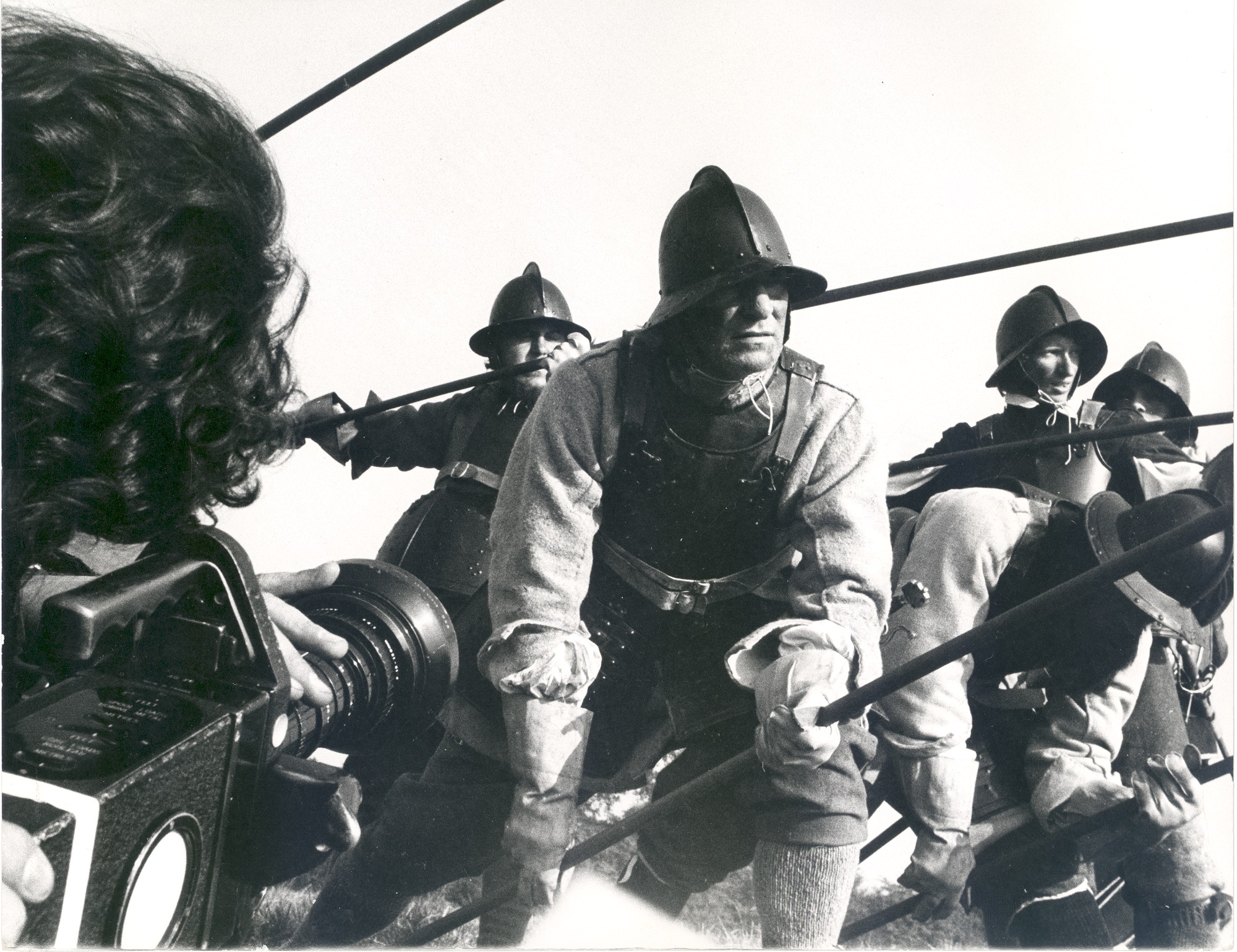 Black and white photograph still of the filming of a battle scene in the film - Winstanley (1975) - showing a group of men fighting the character Tom Haydon, played by Terry Higgins.
