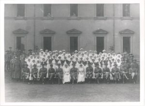 A photograph of Mount Felix Military Hospital, taken sometime between 1915-20. In this official photo, a large group of nurses and patients stand outside the building, while some too unwell to join them look out from the windows.
