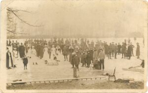 A sepia postcard of the Broadwater, in Weybridge, which had frozen over during one winter in the First World War. Numerous locals stand on the ice, mixing happily with the staff and patients from the New Zealand Military Hospital at Mount Felix. On the back of the postcard, a note reads that nurse Henderson was holding the reins of the sleigh.