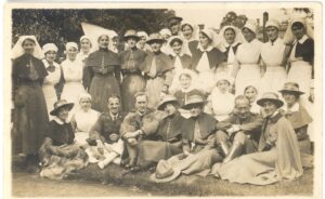 A postcard of Walton showing nursing staff of the New Zealand Military Hospital at Mount Felix, posing for a group photograph with some army personnel. Several are seated, the rest are standing, and the nurses wear traditional First World War nursing uniforms.