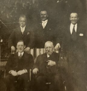 Photograph belonging to Jan Birrell showing some Geesing family members. Jan's grandfather, Pierre Geesing (1862-1937) is in the bottom right. He was the grandson of Peter Geesing of Apps Court. The other people in the photo are (top row left to right), Jan's father, Jan's grandfather on her mother’s side (Richard Henly 1865-1941), and Jan's uncle. Another of Jan's uncles is seated in the bottom row on the left.