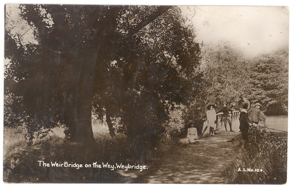 Copy of postcard sent to Master N Monger in Sherbourne St John, postmarked Weybridge 8th June 1911. There is a large tree to the left of the bridge on which there are four boys and two girls, one boy is fishing.