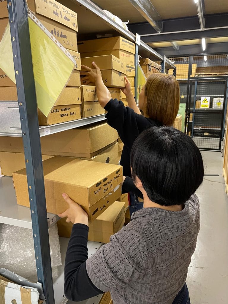 Elly and Cloris looking through boxes of items at the Museum store.