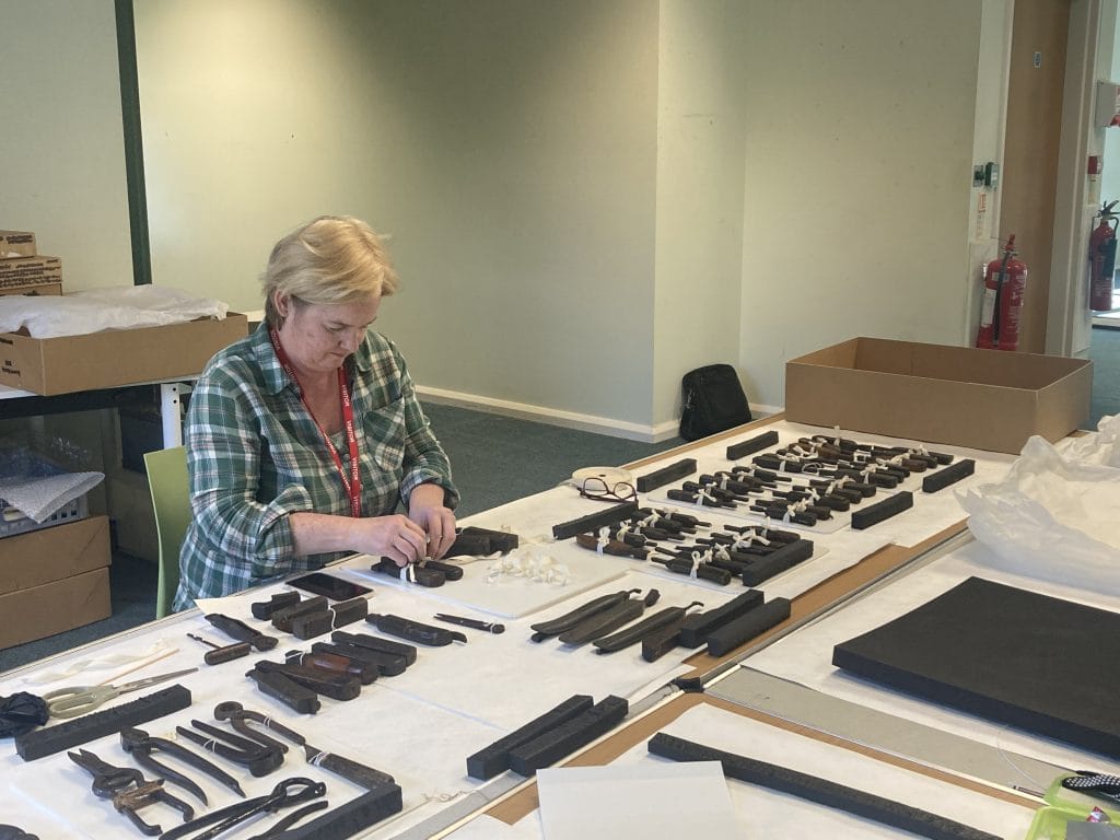 A volunteer assisting with repacking the cobblers tool collection.